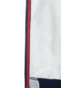 Intérieur de veste zippée rouge et marine avec une texture douce semblable à de la polaire. Dispose d'une doublure blanche unie et d'un ourlet inférieur à rayures horizontales.