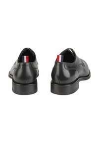 Schwarze Lederschuhe mit glatter Oberfläche, klassischem Design, runder Zehenform und kontrastierendem Akzent in Rot, Weiß und Blau an der Ferse.