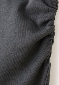 Țesătură gri, texturată, cu model de tricot ribbed și detalii strânse pe o parte, indicând un material moale și elastic.