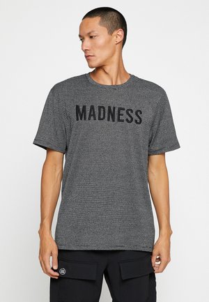 Zwart-wit gestreept T-shirt met korte mouwen, ronde halslijn en grote "MADNESS" tekst in het zwart over de borst.