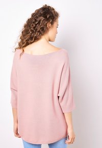 Hellrosa, gerippter Pullover mit weiter Ausschnittöffnung und 3/4-Ärmeln, der eine lockere Passform und einen sanft abgerundeten Saum bietet.