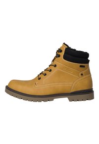 Bottines en cuir tan avec un col rembourré noir, un devant lacé et une semelle robuste. Des surpiqûres blanches soulignent le design. Convient pour une utilisation en extérieur.