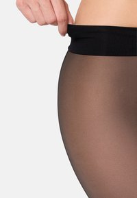 Schwarzer Bund oben, transparente braune Strumpfhose mit glatter Textur. Der Stoff wirkt leicht glänzend und figurbetont.