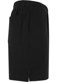 Jupe noire longueur genou avec taille élastique, grande poche plaquée à l'arrière et fente latérale sur fond blanc uni.