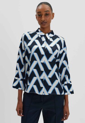 Gekraagde blouse van satijnen stof, met een geometrisch blauw en wit patroon op een marineblauwe achtergrond. Driekwart mouwen met slits.