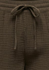 Barna, texturált szövetnadrág elasztikus derékpánttal és elöl megkötött zsinórral.