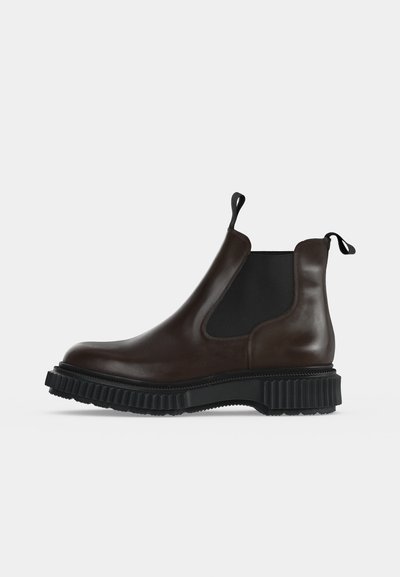 Botte Chelsea en cuir marron foncé avec panneaux latéraux élastiques noirs, languettes de tirage et semelle épaisse en caoutchouc noir rainurée.