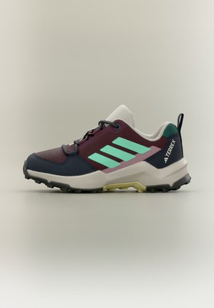 Trailrunning-Schuh mit lila Mesh, türkisfarbenen Streifen, beiger Sohle und schwarzer robuster Außensohle, entwickelt für Outdoor-Aktivitäten.
