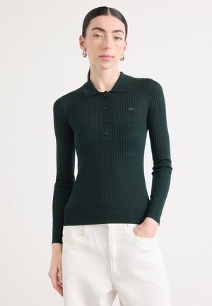 Polo shirt in maglia a coste verde scuro con placca bottoni, maniche lunghe e silhouette aderente. Dettaglio logo piccolo sul petto.