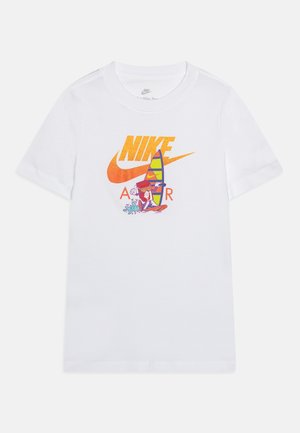 T-shirt blanc Nike avec un logo swoosh orange et un texte, présentant un personnage de dessin animé coloré faisant de la planche à voile devant le logo.