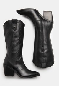 Bottes de cow-boy en cuir noir avec un bout pointu, des détails sculptés, une fermeture éclair sur le côté et un talon empilé. Texture lisse avec une couture décorative.