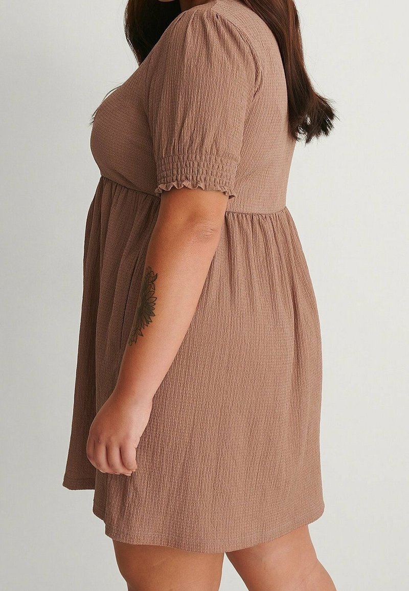 Robe marron texturée avec manches courtes bouffantes et silhouette évasée, présentant des détails froncés au niveau de la poitrine et de la taille.