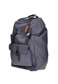 Zaino navy con tessuto texturizzato, spallacci regolabili, tasca anteriore e accessori neri. Presenta un'etichetta di marca per l'identificazione.