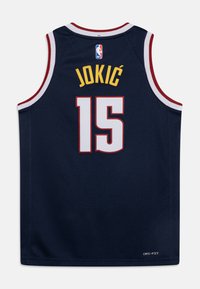 Marinblå baskettröja med röda accenter. Har namnet "JOKIĆ" och nummer "15" i vitt och gult. Tillverkad av fuktavvisande tyg.