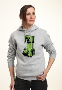 Sudadera gris con un gráfico colorido de un Creeper verde con acentos negros, patrones detallados y capucha con cordón.