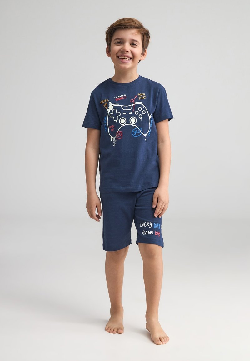 Set di pigiama in cotone blu navy composto da una maglietta a maniche corte con una grafica di un controller di gioco e testo, e pantaloni corti coordinati con la stampa "Ogni giorno è un giorno di gioco".