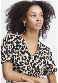 Leopardenmuster-Bluse mit V-Ausschnitt, kurzen Ärmeln und strukturiertem Stoff in Schwarz, Gold und Cremefarben; lässige Passform.