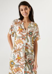 Kurzes, ärmelloses Blumenkleid in Creme mit lebhaften orangefarbenen, blauen und grünen Mustern, mit V-Ausschnitt und lässiger Passform. Weicher Stoff.