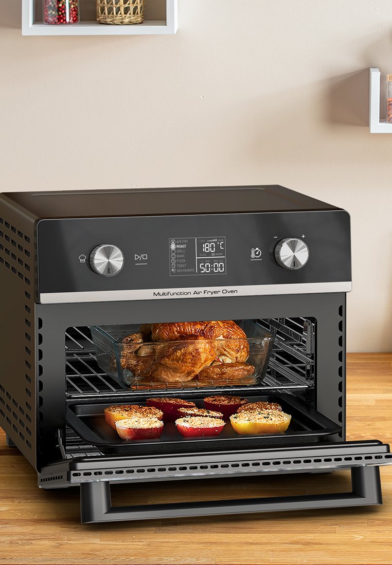 Zwarte multifunctionele heteluchtfriteuse oven met een digitaal display en knoppen, met daarin een gebraden kip en kleurrijke gebakken gerechten.