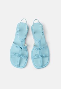 Light blue sandals with a flat sole, featuring thin straps and bows for detail. Made from smooth leather, with an open back design.