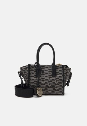 Bolso tote de diseñador en negro y beige con patrón repetitivo del logo, asas negras, correa desmontable y colgante metálico redondo con el logo.