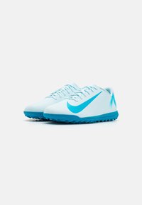 Pár světle modrých fotbalových bot Nike s modrými podešvemi a velkým tikem Nike na boku, na čistém bílém pozadí.