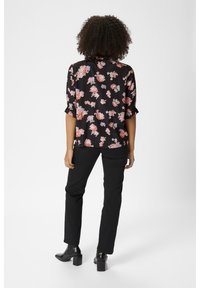 Czarna bluzka w kwiaty z krótkimi rękawami i zaokrąglonym dołem. Posiada różowe i niebieskie wzory kwiatowe na tkaninie przypominającej satynę. Zestawiona z czarnymi spodniami.