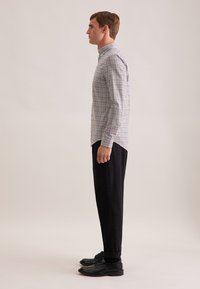 Koszula w kratkę z kołnierzykiem i długimi rękawami, zestawiona z ciemnymi, zwężanymi spodniami i czarnymi butami eleganckimi. Gładki materiał, dopasowany krój.