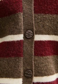 Gilet tricoté dans des nuances de bordeaux, marron et crème avec des rayures horizontales. Il présente un matériau en laine texturé et des accents de boutons marron.