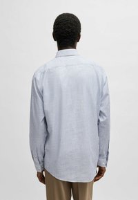 Blauwe en witte gestreepte blouse met lange mouwen, een button-down kraag, manchetten en een relaxte pasvorm. Gemaakt van een lichte, gladde stof.