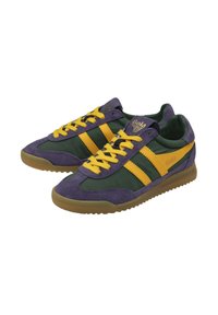 Un par de zapatillas bajas con gamuza morada, tela verde y rayas y cordones amarillos, con suelas de goma marrones.