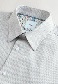 Világosszürke, texturált, vékony szabású ing, 100% pamutból. Virágmintás belső gallérral és fehér gombokkal.