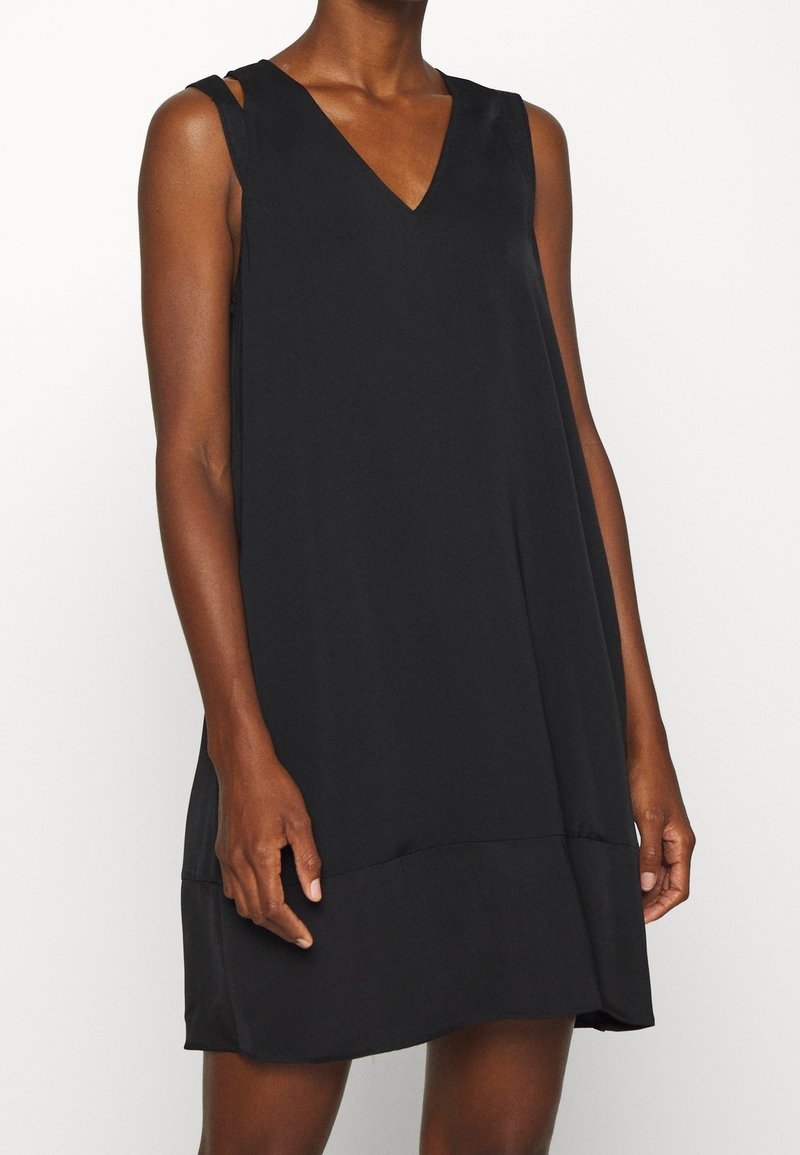 Vestido negro sin mangas con escote en V, silueta fluida y diseño minimalista. Presenta tirantes y dobladillo recto. Textura de tela suave.