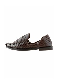 Zapato de cuero marrón sin cordones con diseño trenzado, suela plana, punta redonda y lados abiertos para ventilación. Textura suave con un acabado sutilmente brillante.