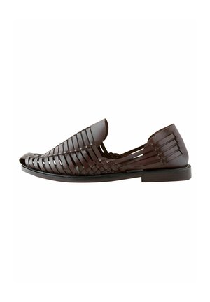 Brown leather slip-on shoe with woven design, flat sole, rounded toe, and open sides for ventilation. Smooth texture with subtle sheen.