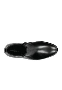 Schwarzer Lederschuh mit glatter Oberfläche, spitzer Zehe und elastischen Seitenakzenten. Das Innere verfügt über ein weiches Futter, auf dem der Markenname "wojas" sichtbar ist.