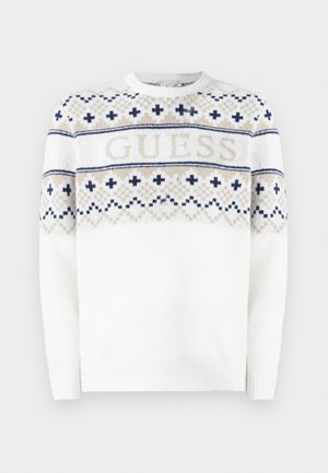 Hvit strikket genser med et geometrisk mønster i marineblått og beige, med ordet "GUESS" på brystet. Rund hals og ribbede mansjetter.