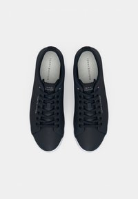 Baskets navy avec une tige synthétique lisse, bout rond, semelle en caoutchouc blanche et lacets. Présente le logo de la marque près du talon et sur la languette.