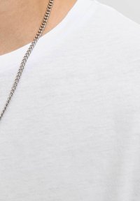 Witte katoenen t-shirt met een ronde hals; heeft een gladde textuur. Een zilveren ketting hangt net boven de halslijn.