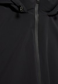 Čierna bunda s mäkkou vonkajšou vrstvou, vybavená predným zipsom, nastaviteľnou kapucňou so sťahovacími šnúrkami, hladkou textúrou a minimálnymi švami.