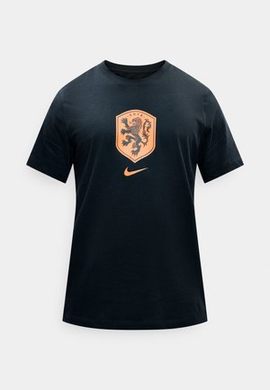 Černé tričko s krátkými rukávy s oranžovým erbem lva KNVB a logem Nike Swoosh na hrudi, jednobarevné pozadí.