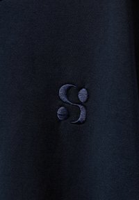 Námornícka bavlnená tričko s hladkou textúrou, na ľavej strane s tmavomodrým vyšívaným logom. Jednoduchý, minimalistický dizajn.