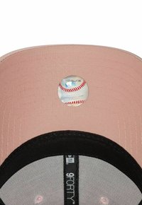 Baseball kapa s ruzičastim rubom, crnim donjim dijelom i sivom mrežom. Ima okruglu MLB naljepnicu koja izgleda kao baseball na vrhu.