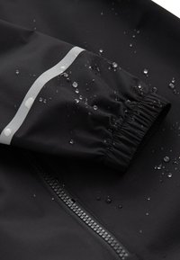 Black waterproof jacket sleeve with elastic cuff, featuring a silver reflective stripe and water droplets on a smooth, matte fabric.