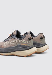 Chaussures de trail running en gris et beige avec une tige en mesh texturé, des accents orange, une semelle intermédiaire rembourrée et une semelle en caoutchouc avec des motifs de grip.