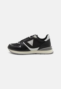 Zapatilla negra con un diseño elegante, que combina cuero y tela. Presenta una superficie texturizada, detalles en plata y una suela de goma para mayor tracción.