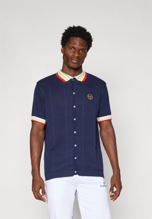 Marineblauw geribd polo shirt met een meerkleurige gestreepte kraag en manchetten, voorzien van een klein logo en knoopsluiting aan de voorkant. Korte mouwen.