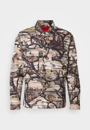 Langermet skjorte med et kamuflasjemønster med grener, blader og fugler. Laget av mønstret stoff med knapper og to frontlommer.