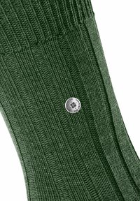 Dunkelgrüner gerippter Strickstoff mit einem kleinen runden silbernen Metallknopf, der mit eingraviertem Text und einem Kreuzsymbol versehen ist.