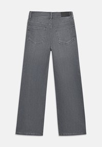 Jeans de ganga cinza de perna larga com uma textura suave, cinco bolsos e um emblema preto na cintura. Vista traseira mostrada.